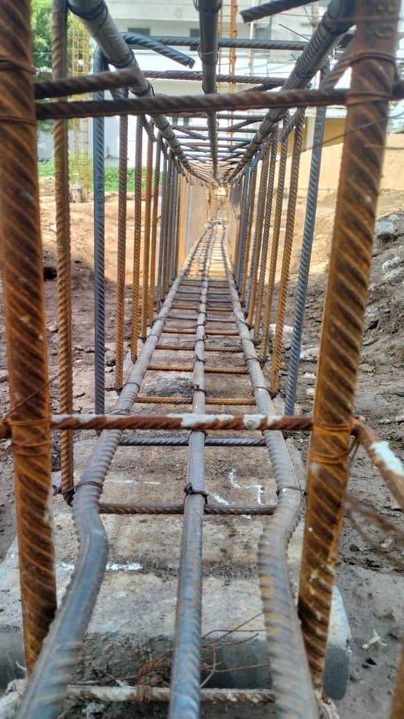 A plinth beam reinforcement cage photographed along its length, stirrups receding to a vanishing point.